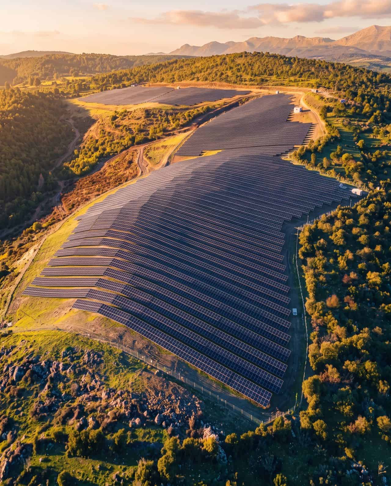 Grand parc solaire avec panneaux photovoltaïques dans un paysage montagneux.